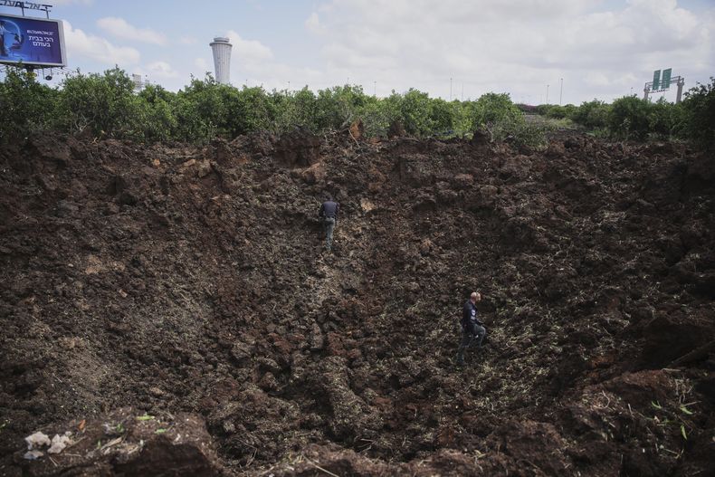 Miembros de las fuerzas de seguridad de Israel inspeccionan un cráter en los terrenos del Aeropuerto Internacional Ben Gurion causado por lo que el ejército israelí dijo fue un proyectil lanzado por los rebeldes hutíes de Yemen el domingo 4 de mayo de 2025. (AP Foto/Ohad Zwigenberg)
