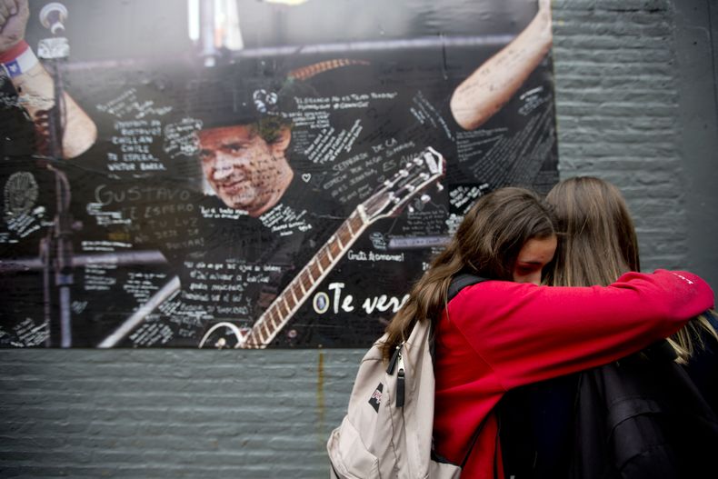 Dos j&oacute;venes se abrazan en llanto ante un p&oacute;ster del m&uacute;sico argentino Gustavo Cerati colocado sobre la pared de la cl&iacute;nica donde estaba internado en Buenos Aires el jueves 4 de septiembre de 2014. Cerati muri&oacute; el jueves a