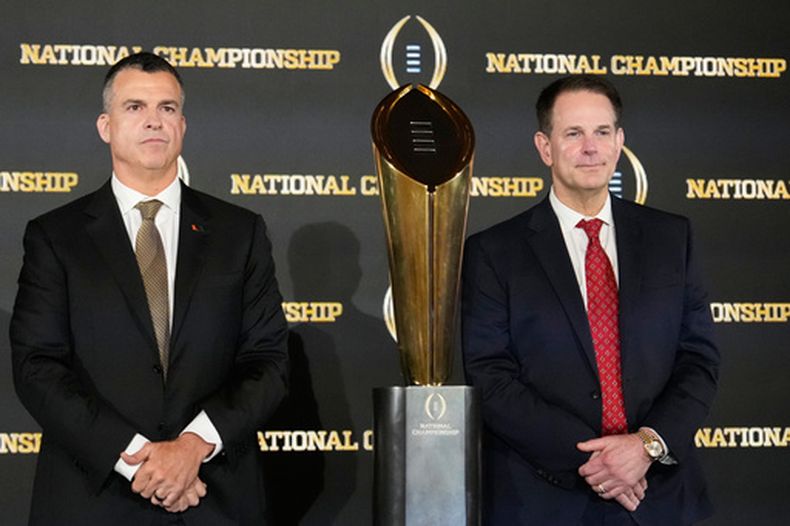 Mario Cristobal, izquierda, entrenador de Miami, y Curt Cignetti, head coach de Indiana, posan con el trofeo del fútbol americano universitario, previo al juego de campeonato de la NCAA entre Miami e Indiana, el domingo 18 de enero de 2026, en Miami. (AP Foto/Chris Carlson)