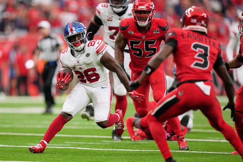 El running back de los Giants de Nueva York, Devin Singletary (26), se escapa de los defensores de los Texans de Houston para anotar el touchdown del triunfo en tiempo extra de un partido de fútbol americano de la NFL en Houston, el domingo 25 de octubre de 2026. (Foto AP/Gerald Herbert)