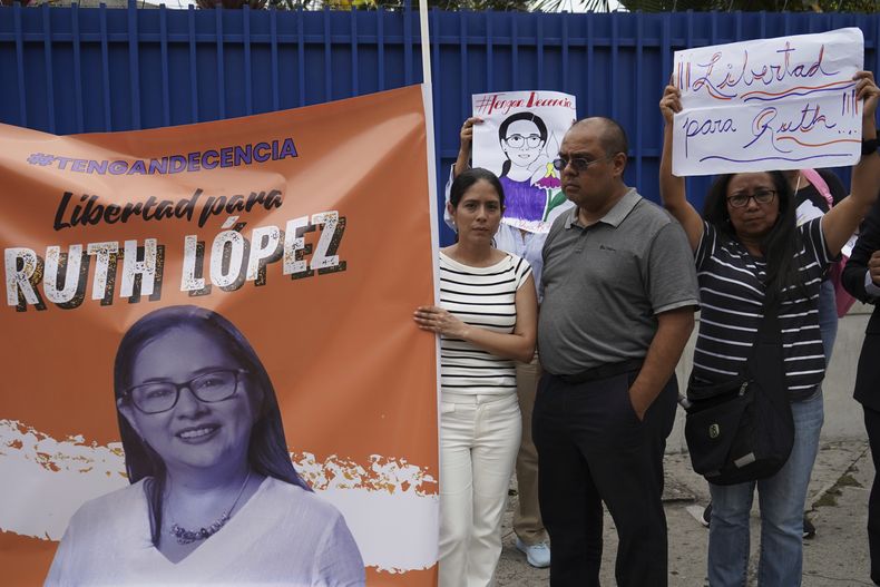 Seguidores de la abogada de derechos humanos Ruth López, detenida en El Salvador, con un cartel de respaldo a las afueras de los tribunales en San Salvador, el miércoles 4 de junio de 2025, el día en que un juez debía decidir si aceptaba los cargos formulados por la fiscalía contra ella por enriquecimiento ilícito. (AP Foto/Salvador Meléndez)