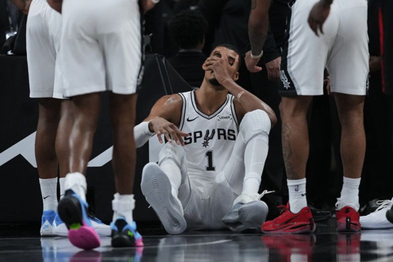 El delantero de los San Antonio Spurs, Victor Wembanyama (1), se sienta en la cancha tras una dura caída durante la primera mitad del segundo juego de una serie de primera ronda de los playoffs de la NBA contra los Trail Blazers de Portland en San Antonio, el martes 21 de abril de 2026. (AP Foto/Eric Gay)
