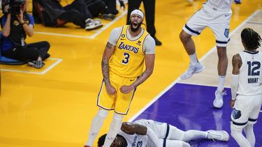 Anthony Davis, de los Lakers de Los Ángeles, festeja su volcada frente a Jaren Jackson, de los Grizzlies de Memphis, quien yace en el suelo en el encuentro de playoffs disputado el viernes 28 de abril de 2023 (AP Foto/Jae C. Hong)