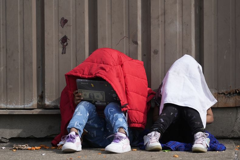 ARCHIVO - Dos niños se cubren la cabeza mientras permanecen afuera de un refugio para migrantes, el miércoles 13 de marzo de 2024, en el vecindario Pilsen de Chicago. (AP Foto/Erin Hooley, archivo)