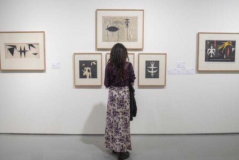 Un visitante observa obras de arte del pintor afrocubano Wifredo Lam en el Museo Mohammed VI de Arte Moderno y Contemporáneo en Rabat, el lunes 1 de abril de 2024. La exposición es una de las primeras de arte cubano en un museo africano. (Foto AP/Mosaab Elshamy)