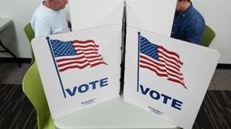 Dos personas cubren sus boletas en un centro de votación instalado en la Biblioteca Regional Tysons-Pimmit, en Falls Church, Virginia, el 31 de octubre de 2024. (AP Foto/Stephanie Scarbrough)