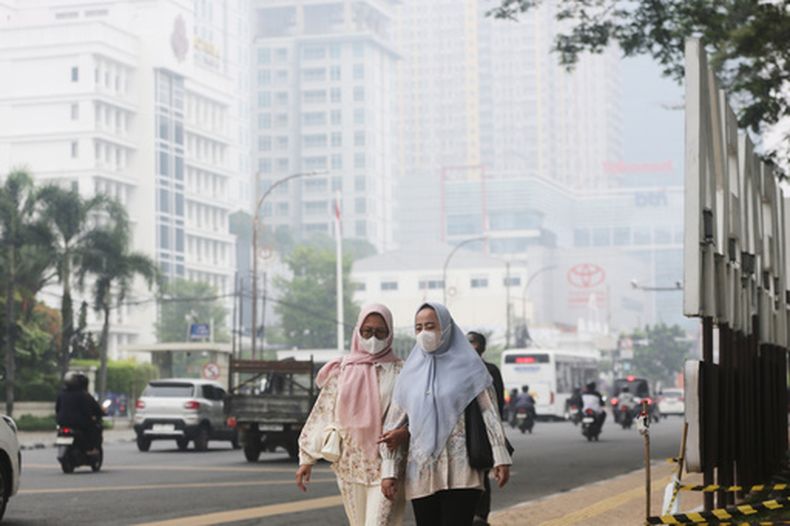 Dos mujeres caminan por una calle mientras el humo de los incendios cubre la ciudad de Medan, en Sumatra Norte, Indonesia, el 15 de octubre de 2026. (AP Foto/Binsar Bakkara)