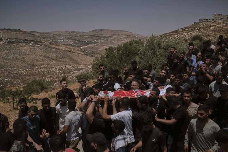 Dolientes cargan los cuerpos de tres palestinos asesinados el miércoles, cuando colonos judíos asaltaron el poblado de Kafr Malik, en Cisjordania, el jueves 26 de junio de 2025. (AP Foto/Leo Correa)