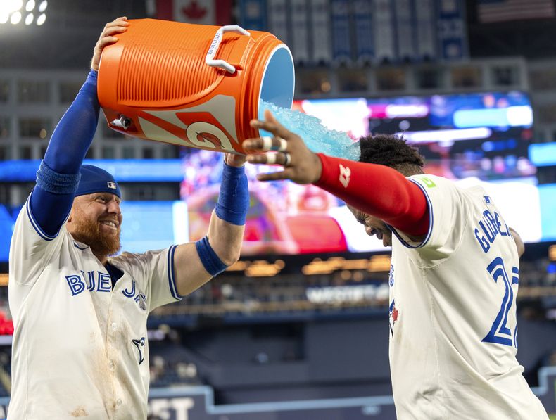 Justin Turner, de los Azulejos de Toronto moja con bebida hidratante a su compañero de equipo el dominicano Vladimir Guerrero Jr. luego de vencer a los Yankees de Nueva York en el juego de béisbol el sábado 29 de junio de 2024, en Toronto. (Frank Gunn/The Canadian Press via AP)