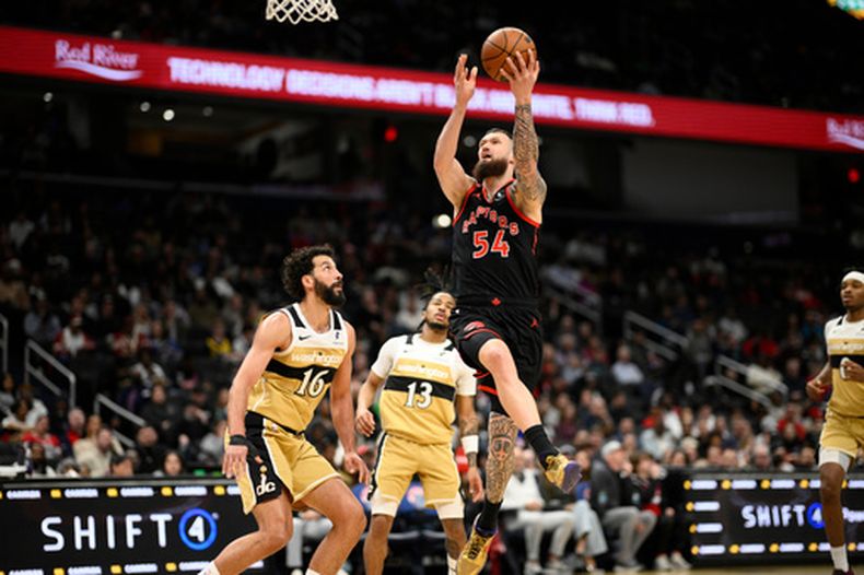 El alero de los Raptors de Toronto Sandro Mamukelashvili salta a la canasta para anotar frente al alero Anthony Gill y el base Sharife Cooper de los Wizards de Washington el sábado 28 de febrero del 2026. (AP Foto/Nick Wass)