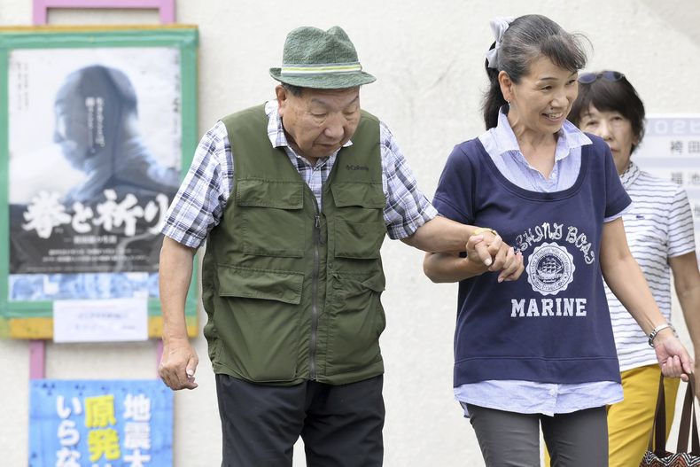 Iwao Hakamada, a la izquierda, un exboxeador que estuvo casi seis décadas en el corredor de la muerte por una condena de asesinato que según sus abogados se basó en una concesión forzosa y pruebas inventadas, recibe ayuda de una defensora para caminar en Hamamatsu, prefectura de Shizuoka, en el centro de Japón, el miércoles 25 de septiembre de 2024. (Kyodo News via AP)