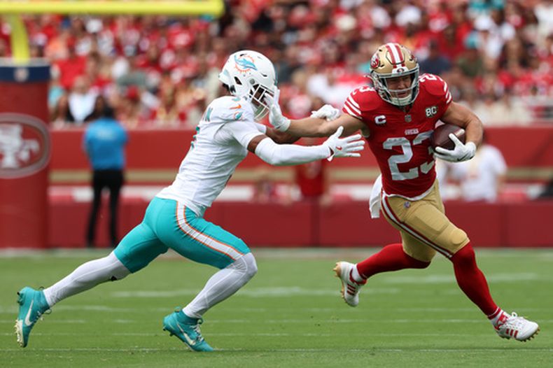 Christian McCaffrey (23), de los 49ers de San Francisco, corre y elude una tackleada de Chris Johnson, de los Dolphins de Miami, durante la primera mitad del juego de la NFL, el domingo 20 de septiembre de 2026, en Santa Clara, California. (AP Foto/Jed Jacobsohn)