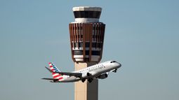 Un avión American Eagle de American Airlines pasa por la torre de control de tráfico aéreo en el Aeropuerto Internacional Phoenix Sky Harbor, el sábado 8 de noviembre de 2025, en Phoenix. (AP Foto/Ross D. Franklin)