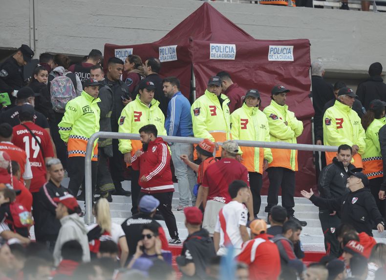 Agentes policiales y empleados de seguridad resguardan la zona donde falleció un espectador, al caer desde la tribuna durante el partido de River Plate contra Defensa y Justicia en Buenos Aires, el sábado 3 de junio de 2023 (AP Foto/Nicolas Aboaf)