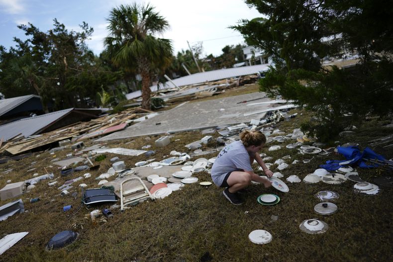Lainey Hamelink, de 9 años, cuya familia era dueña de la propiedad contigua, ayuda a recoger vajilla desparramada en el Tinas Dockside Inn, totalmente destruido por el huracán Idalia en Horseshoe Beach, Florida, 1 de setiembre de 2023, dos días después del paso de la tormenta. (AP Foto/Rebecca Blackwell)
