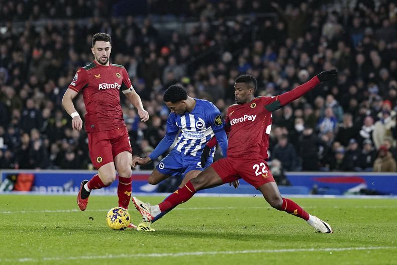 Joao Pedro, de Brighton y Hove Albion, es marcado por Nelson Semedo, de Wolverhampton Wanderers, derecha, en la batalla por el balón durante el partido de fútbol de la Liga Premier inglesa entre Brighton y Hove Albion y Wolverhampton Wanderers en el American Express Stadium, Brighton, Inglaterra, el lunes 22 de enero de 2024. (Adam Davy/PA vía AP)