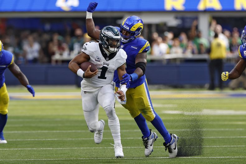 Kobie Turner, derecha, tackle defensivo de los Rams de Los Ángeles, trata de derribar a Jalen Hurts, quarterback de los Eagles de Filadelfia, durante la segunda mitad del juego de la NFL, el domingo 8 de octubre de 2023, en Inglewood, California. (AP Foto/Kevork Djansezian)