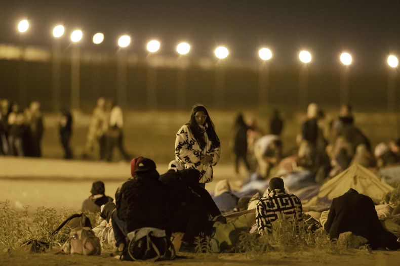 Migrantes esperan al aire libre en una puerta en el muro fronterizo tras cruzar desde Ciudad Juárez, México, a El Paso, Texas, en la madrugada del 11 de mayo de 2023. Los migrantes se apuraron a cruzar la frontera horas antes del final de las restricciones relacionadas con la pandemia del coronavirus el jueves por miedo a que las nuevas políticas migratorias complique más el ingreso al país. (AP Foto/Andres Leighton)