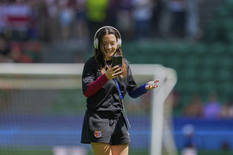 La barcelonista Aitana Bonmatí usa su teléfono inteligente en el campo antes del partido de la final de la Liga de Campeones femenina entre el Arsenal y el FC Barcelona en el estadio José Alvalade de Lisboa, el sábado 24 de mayo de 2025. (AP Foto/Armando Franca)