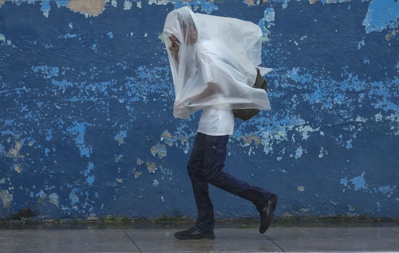 Un hombre camina protegiéndose del viento y la lluvia provocados por el huracán Rafael en La Habana, Cuba, el miércoles 6 de noviembre de 2024. (Foto AP/Ramón Espinosa)