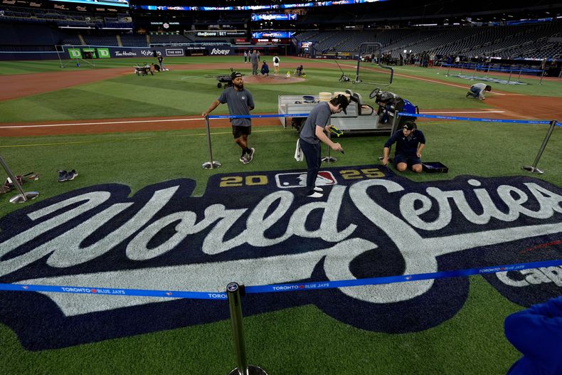 Una cuadrilla alista el logotipo pinado en el terreno del Rogers Centre el jueves 23 de octubre de 2025, un día antes de que comience en Toronto la Serie Mundial (AP Foto/David J. Phillip)