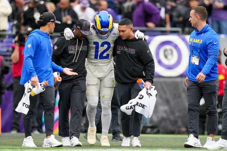 Entrenadores de los Rams de Los Ángeles ayudan al receptor Puka Nacua para salir del campo tras lesionarse en el encuentro ante los Ravens de Baltimore el domingo 12 de octubre del 2025. (AP Foto/Stephanie Scarbrough)
