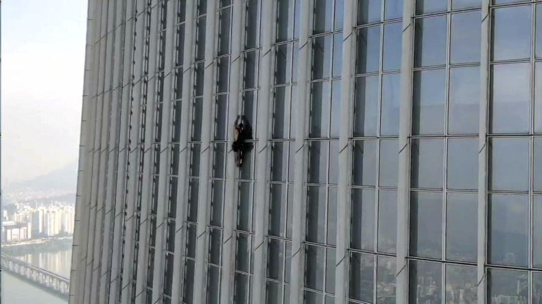 Esta fotografía proporcionada por la oficina de bomberos y manejo de emergencias de la zona metropolitana de Seúl, Corea del Sur, muestra a un británico no identificado mientras escala el rascacielos Lotte World Tower, el lunes 12 de junio de 2023. (The Seoul Metropolitan Fire and Disaster Management Headquarters, via AP).