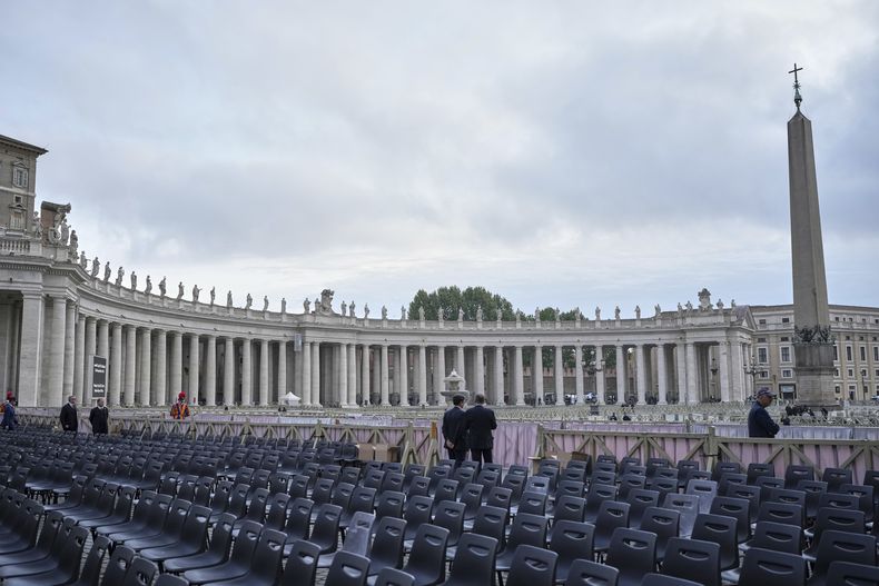 Dos hombres se ven de pie cerca de varias sillas durante los preparativos en la plaza de San Pedro antes de la llegada del cuerpo del papa Francisco, que yacerá en cuerpo presente durante tres días en la basílica de San Pedro, en el Vaticano, el miércoles 23 de abril de 2025. (AP Foto/Alessandra Tarantino)