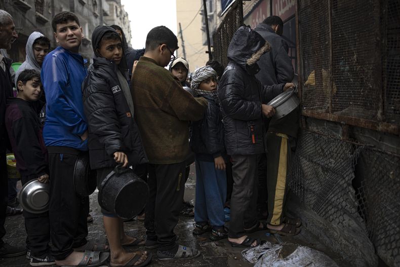 Niños palestinos esperan en una fila para recibir comida en Rafah, en el sur de la Franja de Gaza, el miércoles 13 de diciembre de 2023. (AP Foto/Fatima Shbair)