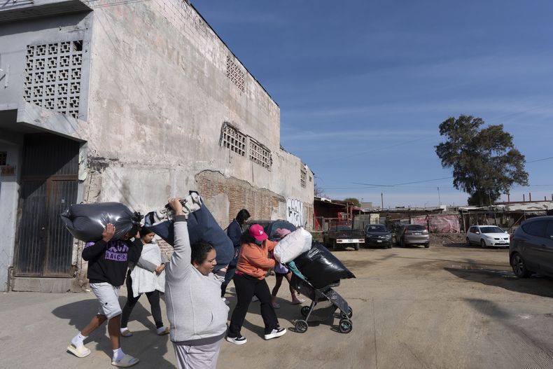 La venezolana Margelis Rodríguez, en el centro, empuja un carrito lleno de ropa mientras su familia y otras personas de un refugio de migrantes caminan a una lavandería cercana en Tijuana, México, el viernes 31 de enero de 2025. (AP Foto/Gregory Bull)