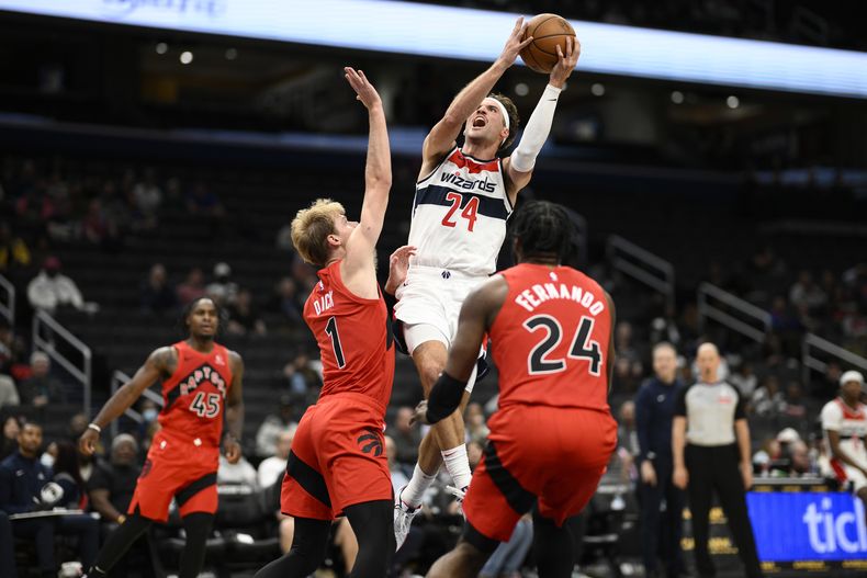 El alero de los Wizards de Washington Corey Kispert (24) va a la canasta contra el escolta de los Raptors de Toronto Gradey Dick (1) y el alero Bruno Fernando (24) durante la segunda mitad de un partido de baloncesto de pretemporada de la NBA, el viernes 11 de octubre de 2024, en Washington. (AP Foto/Nick Wass)