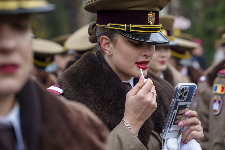 ARCHIVO - Una cadete militar se retoca el labial antes de un desfile del Día Nacional en Bucharest, Rumania el 1 de diciembre de 2023. (Foto AP/Vadim Ghirda, archivo)