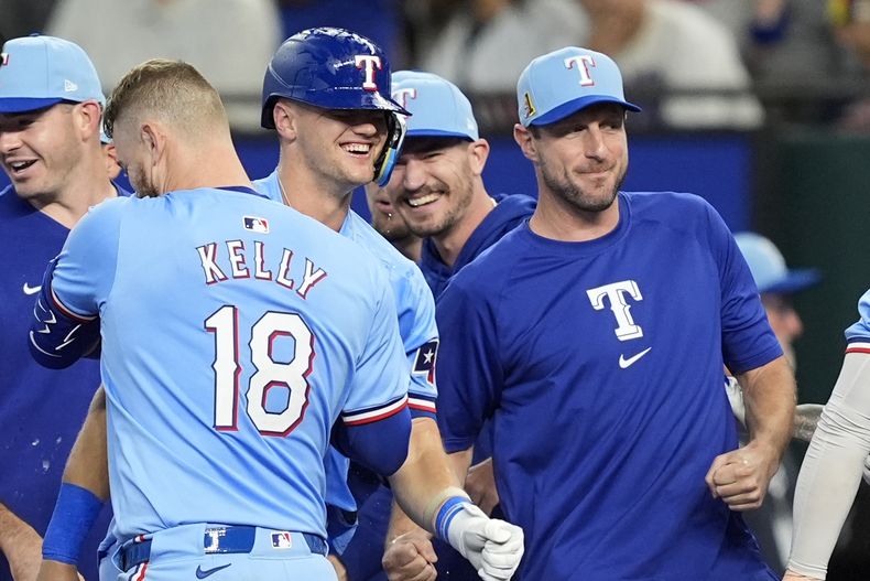 Carson Kelly (18), Josh Jung, centro, y Max Scherzer, derecha, de los Rangers de Texas, celebran en la décima entrada después de la victoria del equipo por 6-5 contra los Mellizos de Minnesota, el domingo 18 de agosto de 2024, en Arlington, Texas. (AP Foto/Tony Gutiérrez)