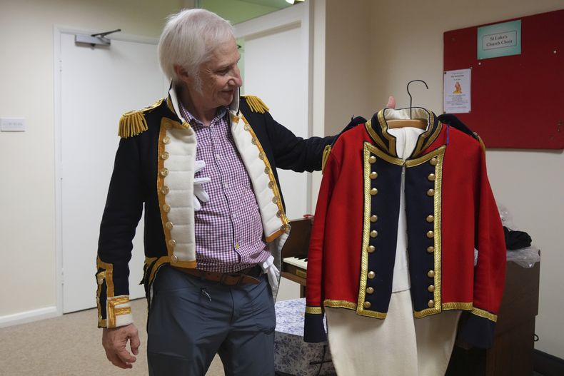Chris Oswald, presidente de los Hampshire Regency Dancers, sostiene un traje de época que confeccionó durante una sesión de práctica de baile de los Hampshire Regency Dancers en Winchester, Inglaterra, el 10 de septiembre de 2025. (Foto AP/Joanna Chan)