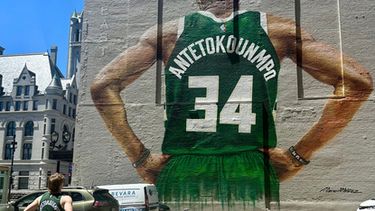 Danny Nelson luce una camiseta de los Bucks de Milwaukee de Giannis Antetokounmpo mientras contempla un mural suyo en el centro de Milwaukee el martes 23 de junio de 2026. (Foto AP/Steve Megargee)