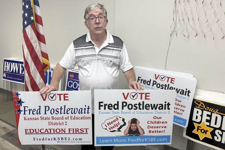 Fred Postlewait, candidato republicano a la Junta Estatal de Educación de Kansas City, Kan, muestra dos carteles disponibles para los partidarios en la sede local del Partido Republicano en el condado de Johnson, el martes 1 de octubre de 2024, en Overland Park, Kansas. (AP Foto/John Hanna)