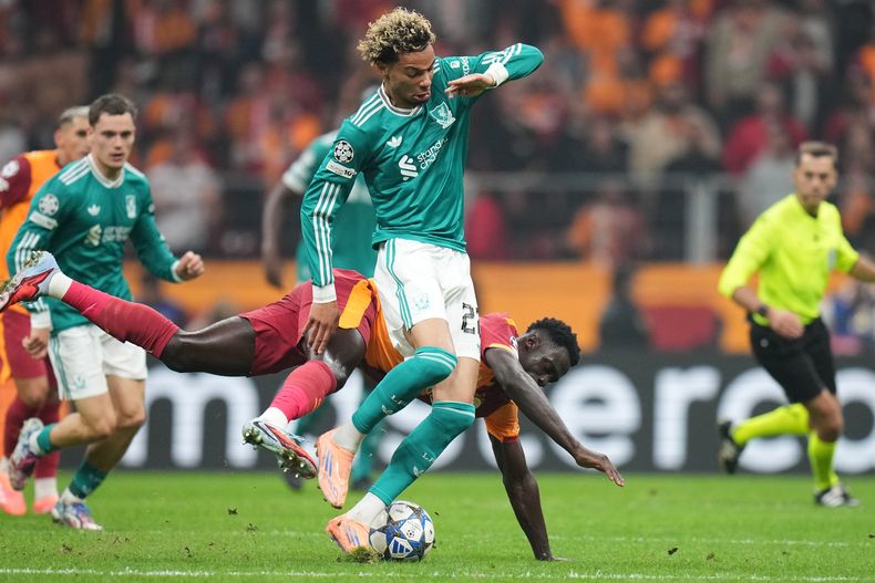Davinson Sánchez de Galatasaray se cae al pugnar por el balón con Hugo Ekitike de Liverpool en el partido de la Liga de Campeones, el martes 30 de septiembre de 2025, en Estambul. (AP Foto/Francisco Seco)