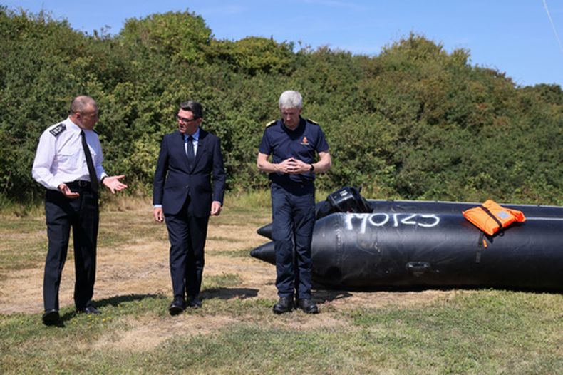 El primer ministro británico, Andy Burnham, en el centro, habla con John Craig, jefe interino de la Guardia Costera, y Duncan Capps, comandante de seguridad de fronteras, a la izquierda, cerca de un pequeño bote recuperado que se utilizó para llevar migrantes desde el otro lado del Canal de la Mancha, durante una visita al Centro de Coordinación de Rescate Marítimo de la Guardia Costera en Dover, Reino Unido, el 2 de agosto de 2026. (Jack Taylor/Pool Foto via AP)