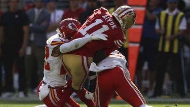 Brandon Aiyuk (11), wide receiver de los 49ers de San Francisco, recibe un golpe de Trent McDuffie, izquierda, y Chamarri Conner, de los Chiefs de Kansas City, durante la primera mitad del juego de la NFL en Santa Clara, California, el domingo 20 de octubre de 2024. (AP Foto/Jed Jacobsohn)