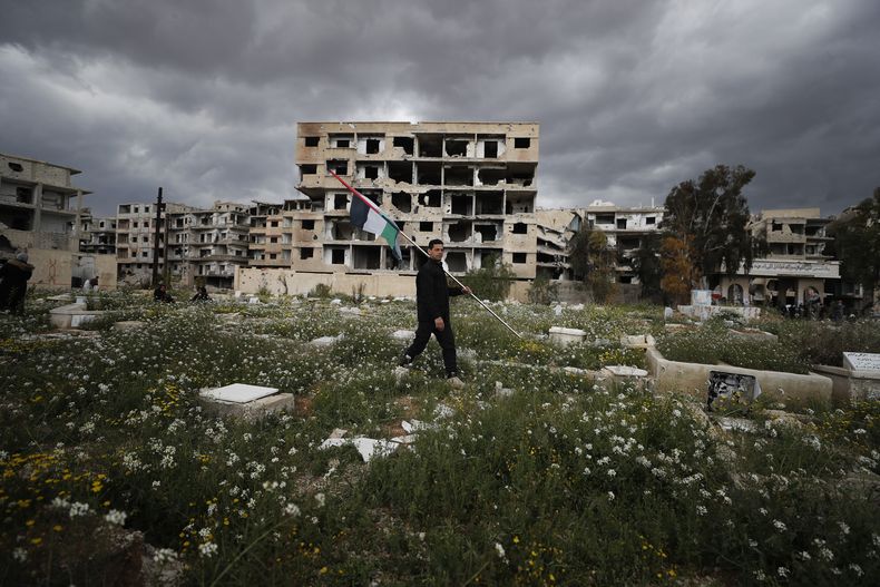 ARCHIVO - Un hombre lleva una bandera palestina en un campo de refugiados palestino en Yarmouk, en Damasco, Siria, el lunes 20 de marzo de 2023. Al menos siete personas fueron detenidas en Alemania y Suecia como sospechosas de cometer crímenes contra la humanidad y crímenes de guerra en Siria entre 2012 y 2014, según dijeron las autoridades de los dos países europeos el miércoles 3 de julio de 2024. (AP Foto/Omar Sanadiki, Archivo)