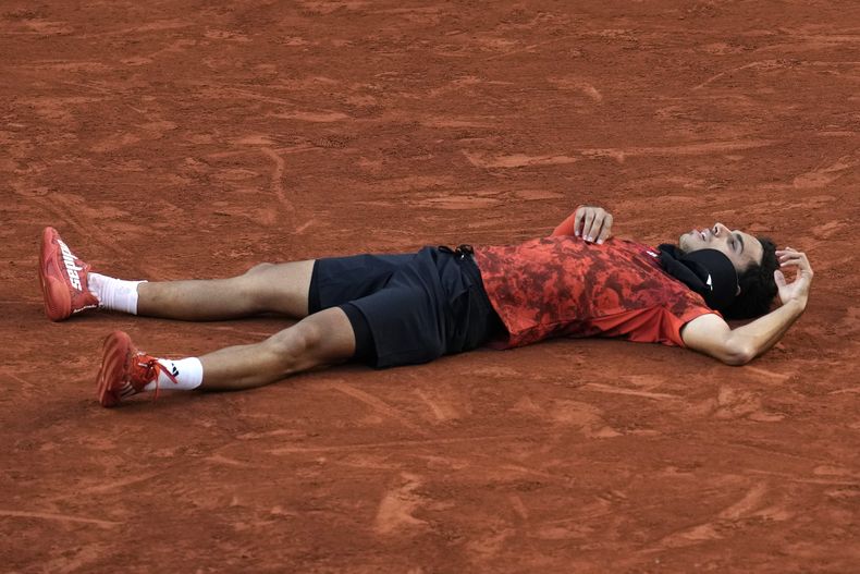 Francisco Cerúndolo tirado en la arcilla tras derrotar a Taylor Fritz en la tercera ronda del Abierto de Francia, el sábado 3 de junio de 2023 (AP Photo/Christophe Ena)
