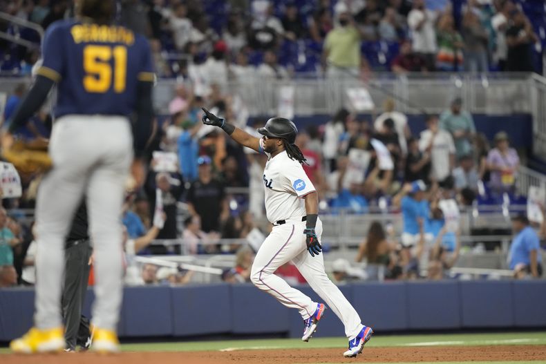 Josh Bell, derecha, de los Marlins de Miami, recorre las bases después de batear un jonrón solitario frente al abridor de los Cerveceros de Milwaukee, Freddy Peralta (51), durante la tercera entrada del juego de béisbol, el domingo 24 de septiembre de 2023, en Miami. (AP Foto/Lynne Sladky)