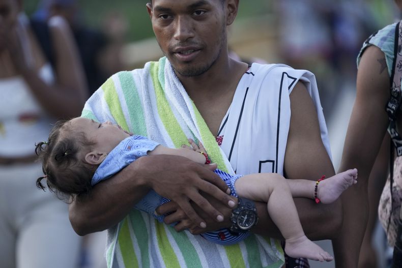 Un migrante sostiene a un niño en sus brazos mientras camina por la carretera Huixtla con la esperanza de llegar a la frontera norte del país y finalmente a Estados Unidos, en Huehuetán, en el sur de México, el miércoles 6 de noviembre de 2024. (Foto AP/Moisés Castillo)