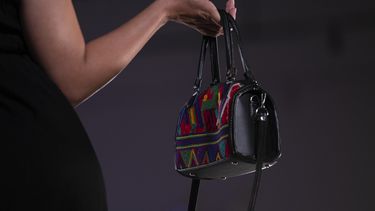 Una modelo muestra un bolso durante un desfile de modas con textiles guatemaltecos, el viernes 12 de mayo de 2023, en Brownsville, Texas. Una diseñadora nacida en Guatemala combinó técnicas indígenas de tejido, diseño moderno de ropa y colorida historia de su país natal en una exhibición reciente en una pasarela de Texas. La presentación ofreció una muestra no sólo de la visión artística de Elena de León, sino un trabajo de madres guatemaltecas, incluidas algunas que viven en Estados Unidos y otras que se quedaron en su país para apoyar a sus familias. (AP Foto/Julio Cortez)