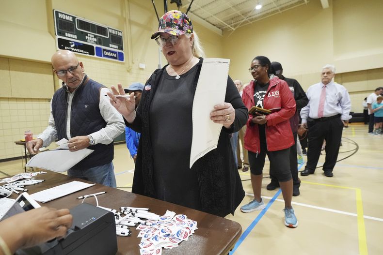 ARCHIVO - Blythe González, a la derecha, hace una pregunta a un trabajador del distrito electoral de Jackson, Mississippi, mientras su marido Jorge González, a la izquierda, espera con su papeleta, para acompañarla a un quiosco de votación, 5 de noviembre de 2024. (AP Rogelio V. Solis, archivo)