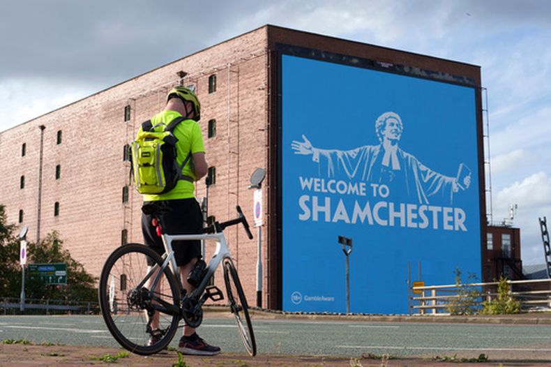 Un apersona toma una foto del anuncio en la calle en referencia al escándalo con el Manchester City el jueves 1 de octubre del 2026. (AP Foto/Jon Super)