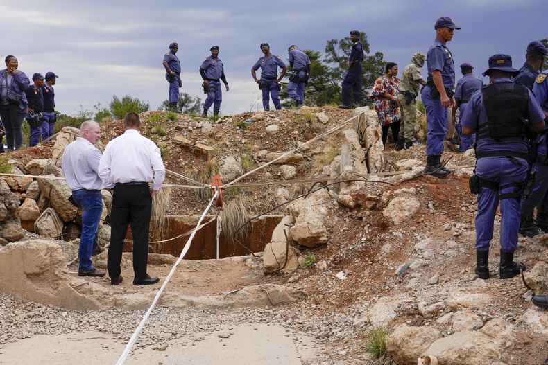 ARCHIVO - Policías y guardias de seguridad privada vigilan el viernes 15 de noviembre de 2024 la salida de un tiro de una mina de oro donde mineros clandestinos quedaron atrapados en Stilfontein, Sudáfrica. (AP Foto/Denis Farrell, Archivo)
