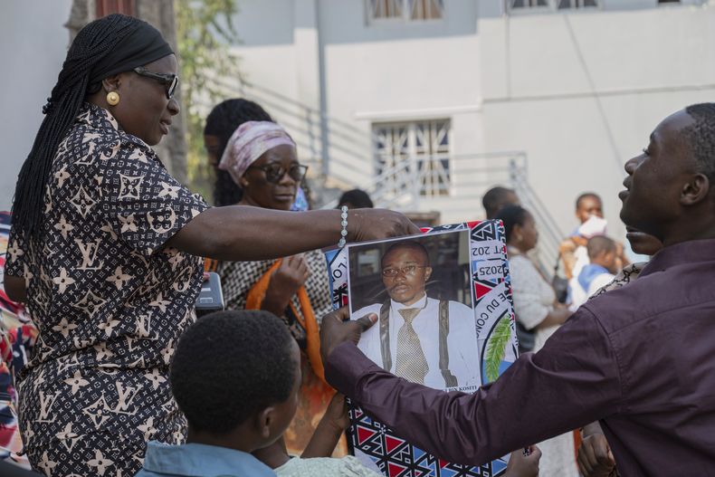 Un grupo de personas ven una tela con el retrato de Floribert Bwana Chui Bin Kositi, en una misa en su honor en una iglesia en Goma, República Democrática del Congo, el 15 de junio del 2025. (AP foto/Moses Sawasawa)