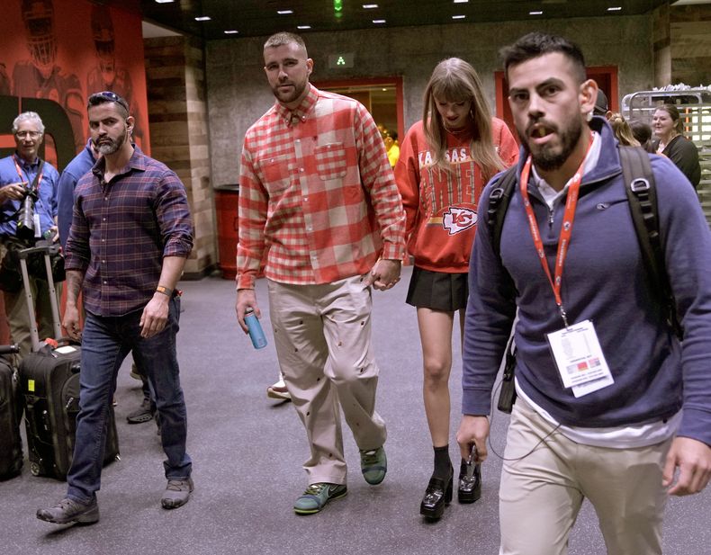 ARCHIVO - El ala cerrada de los Chiefs de Kansas City, Travis Kelce, en el centro a la izquierda, y la cantante Taylor Swift abandonan el estadio Arrowhead después de un partido de fútbol americano de la NFL entre los Chiefs y Chargers de Los Angeles en Kansas City, Mo., el 22 de octubre de 2023. (Foto AP/Charlie Riedel, archivo)