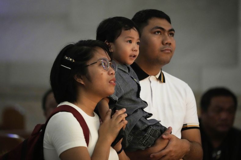 Una familia reza frente a un retrato del difunto papa Francisco, en la Catedral de Manila, Filipinas, el 22 de abril de 2025. (AP Foto/Aaron Favila)